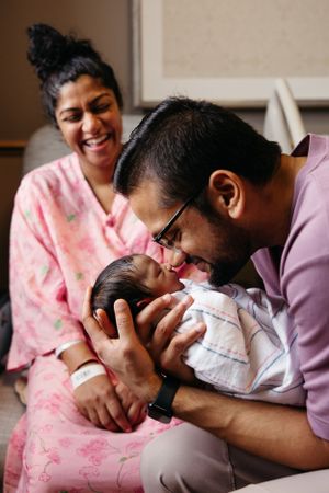 A touching moment between parents and their newborn baby in a hospital room, filled with joy and tenderness.