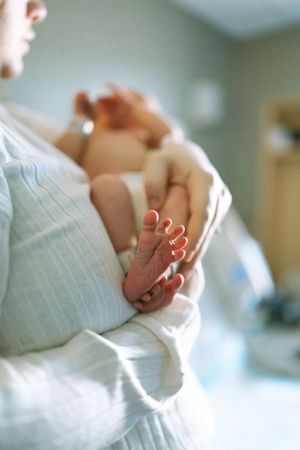 A tiny newborn baby foot rests gently against soft white fabric in a tender moment of care.