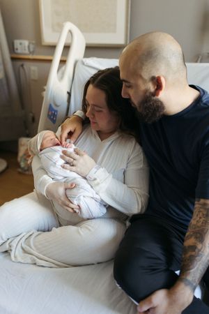 A tender moment in a hospital room as a newborn baby is cradled with care and affection.