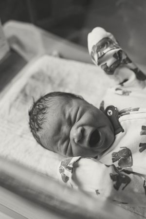 Black and white photographs showing a sleeping newborn baby in a hospital setting.