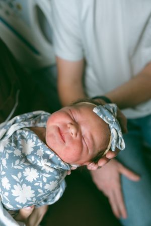Close-up view of a sleeping newborn baby wearing a blue and white floral outfit.