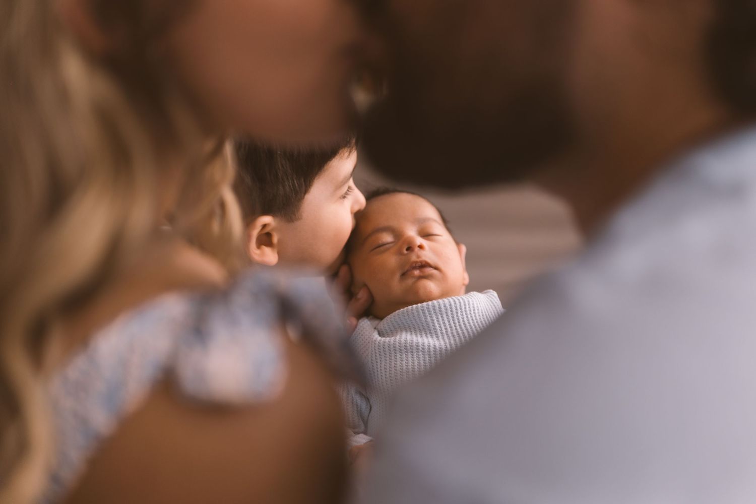 Intimate family moment captured on couch in soft lighting.
