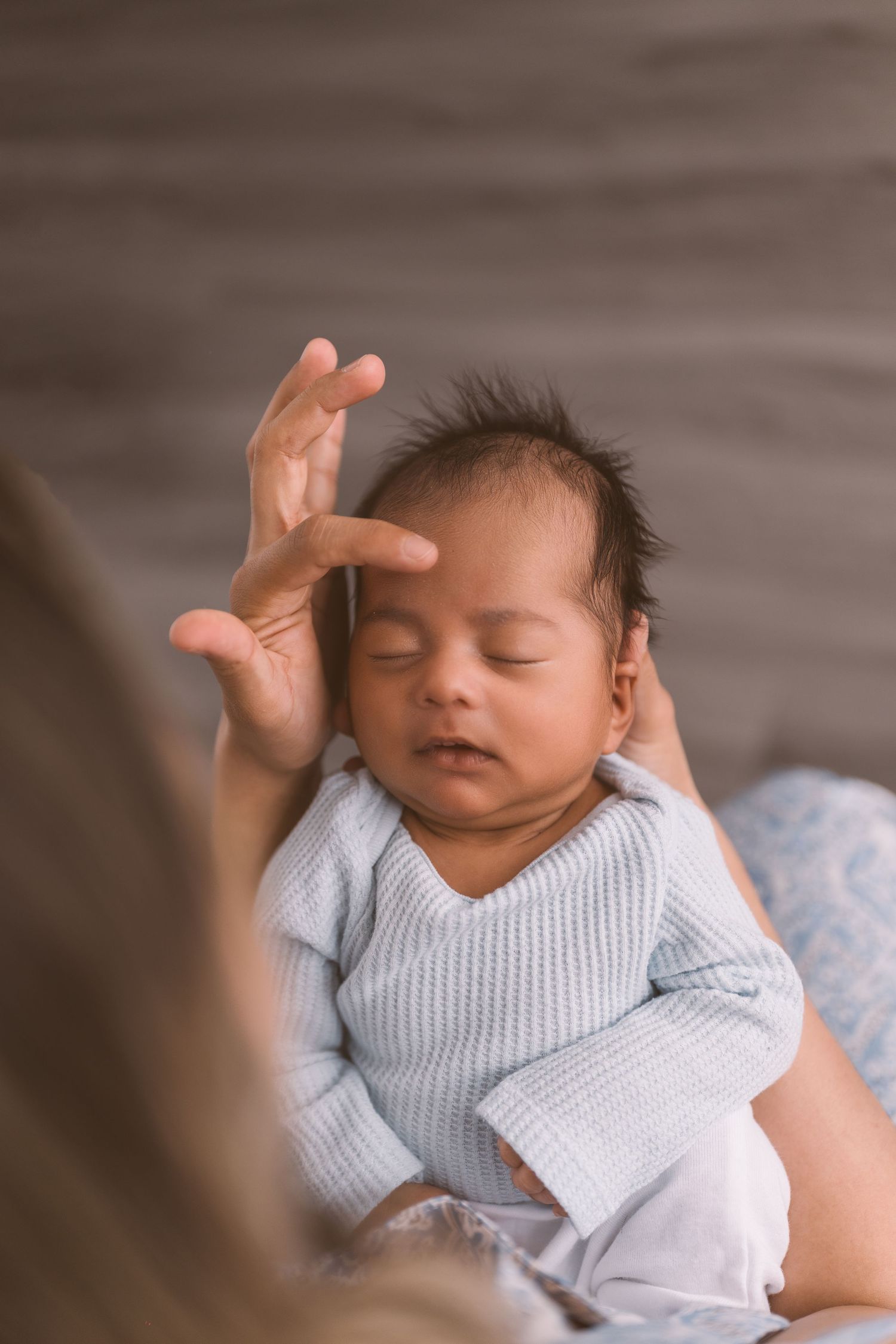 Sleeping infant in light blue knit outfit resting peacefully.