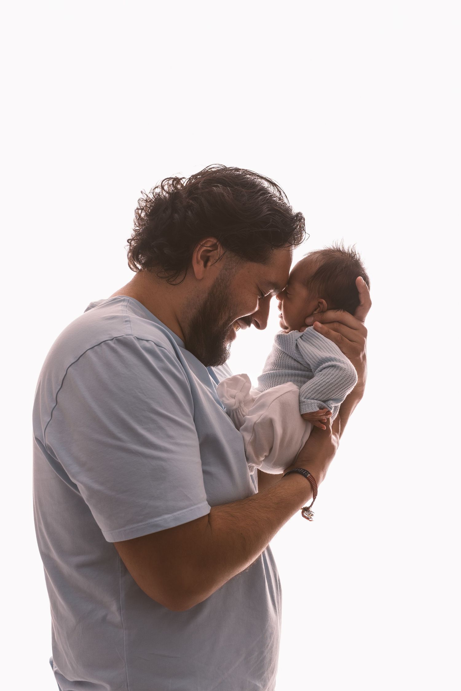 Emotional moment between parent and newborn in white studio setting.
