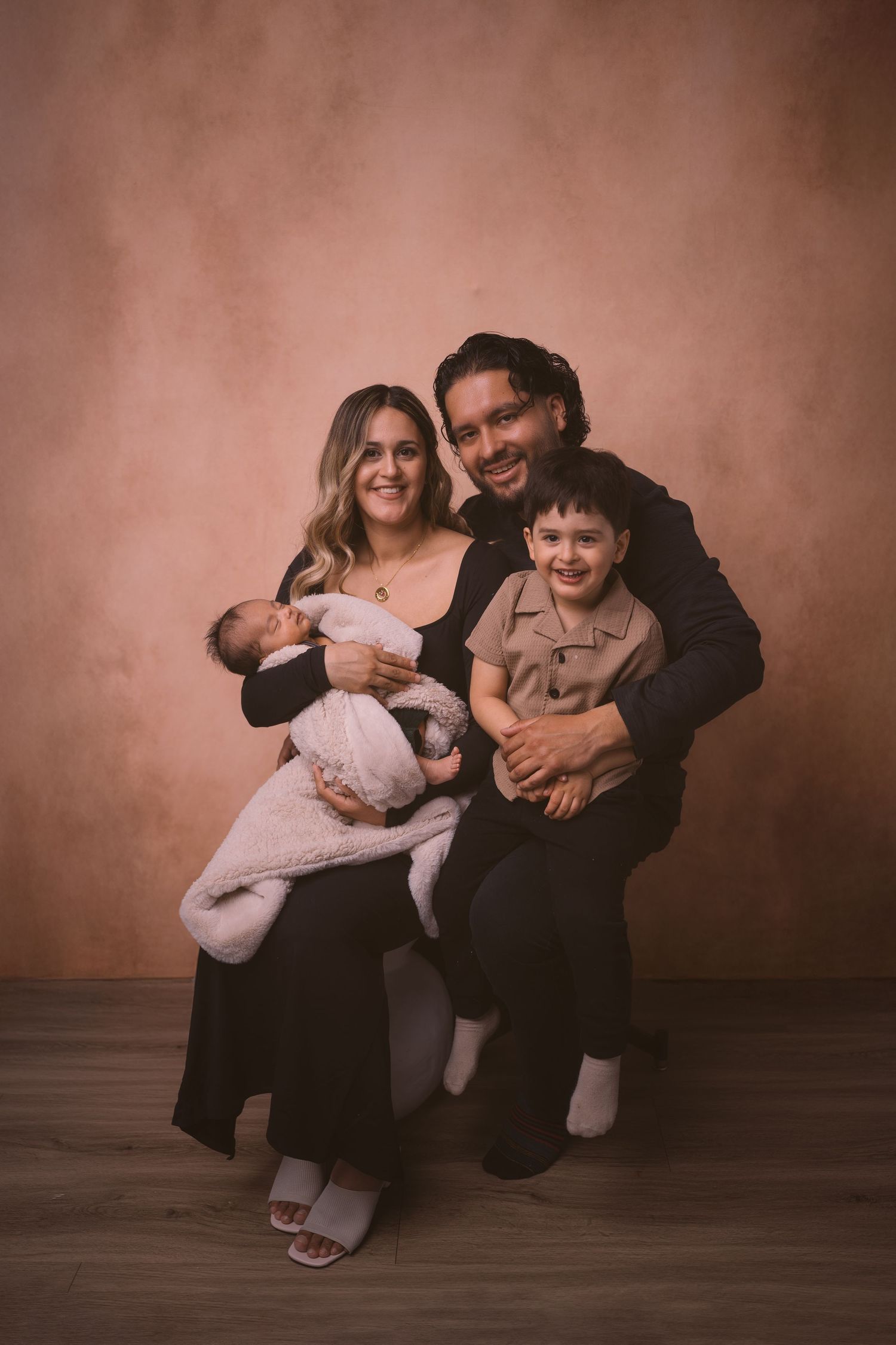 Family photography session showing playful moments between parents and child against dark background.