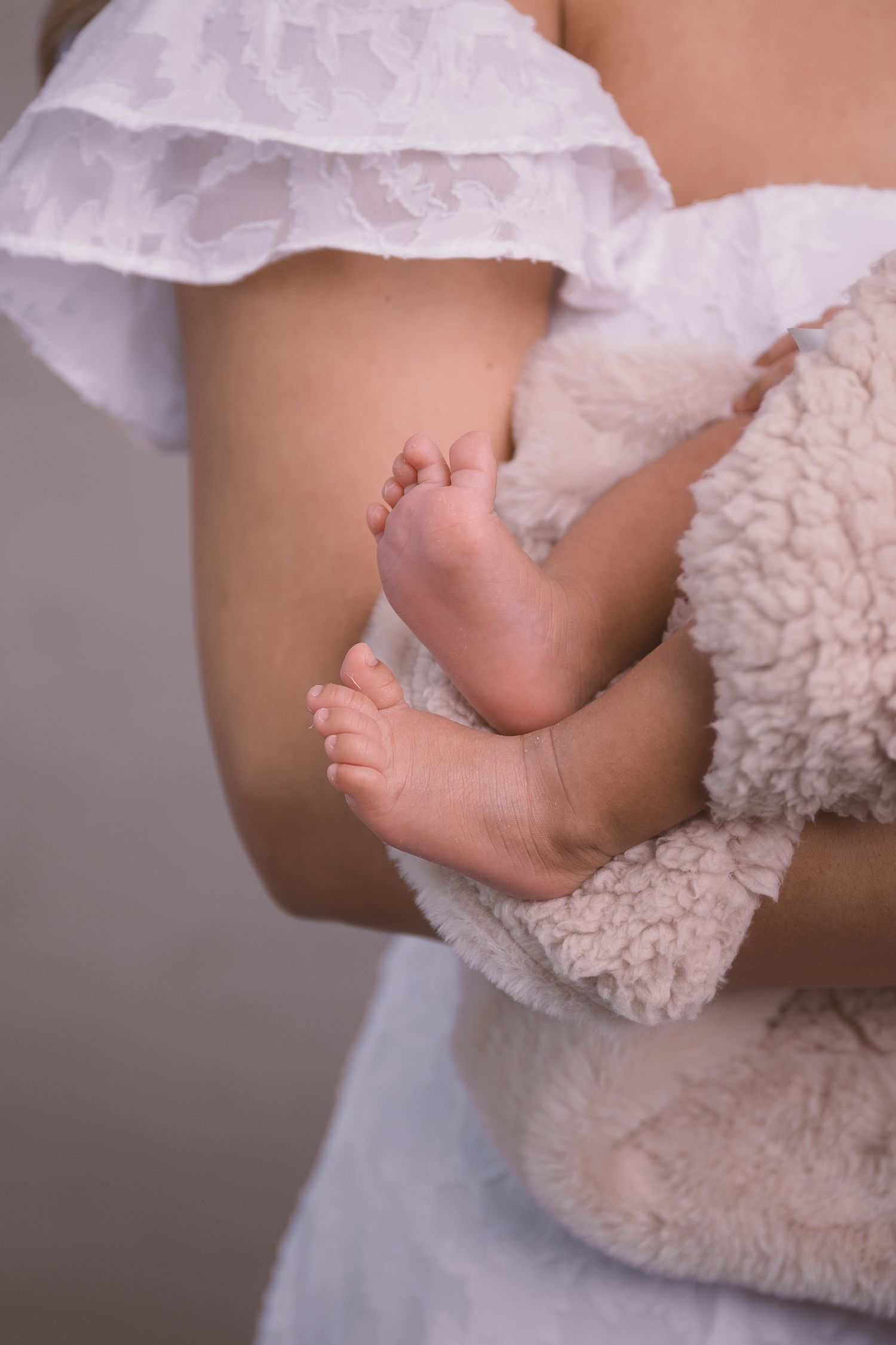 Close-up detail shot of tiny baby feet with white lace fabric.