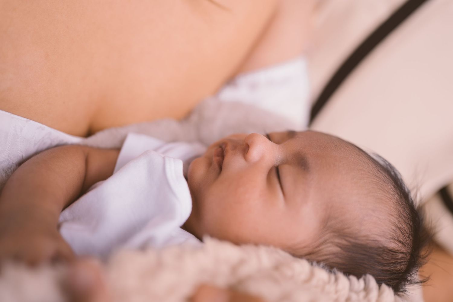 Peaceful sleeping newborn wrapped in soft blankets during professional photo session.
