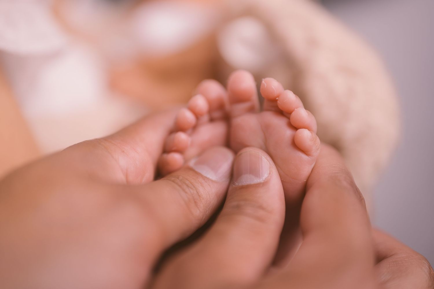 Close-up photograph of tiny baby toes and feet against light background.