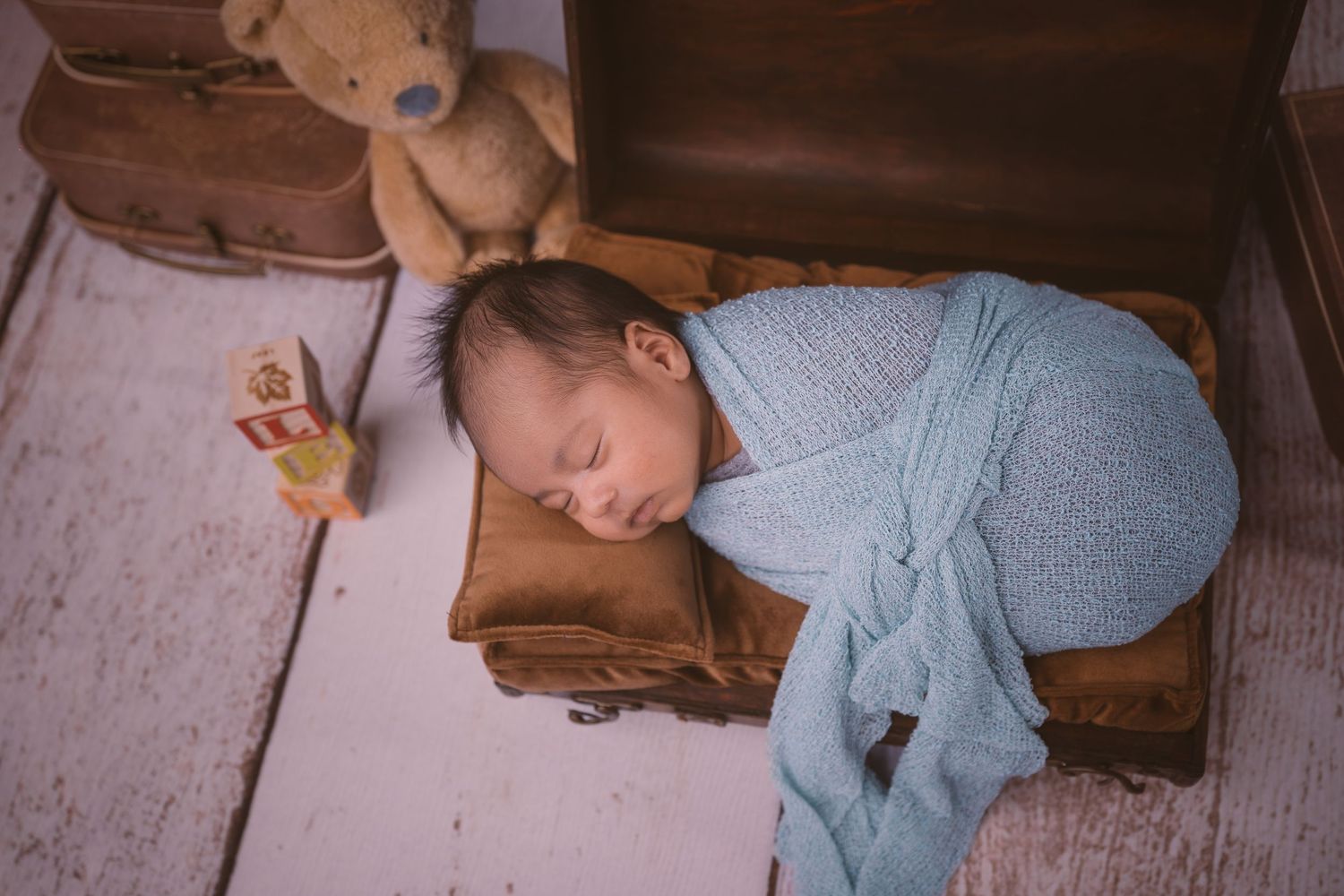 Baby sleeping peacefully on white blanket during professional photo session.