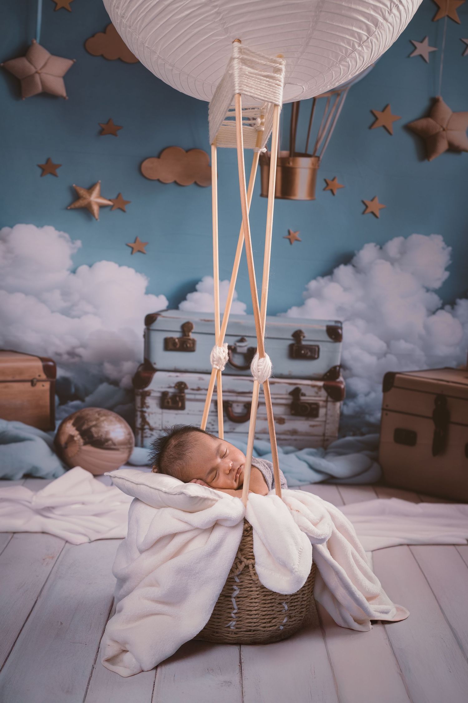Dreamy baby photography setup with white paper lanterns, stars, and clouds against a blue backdrop.