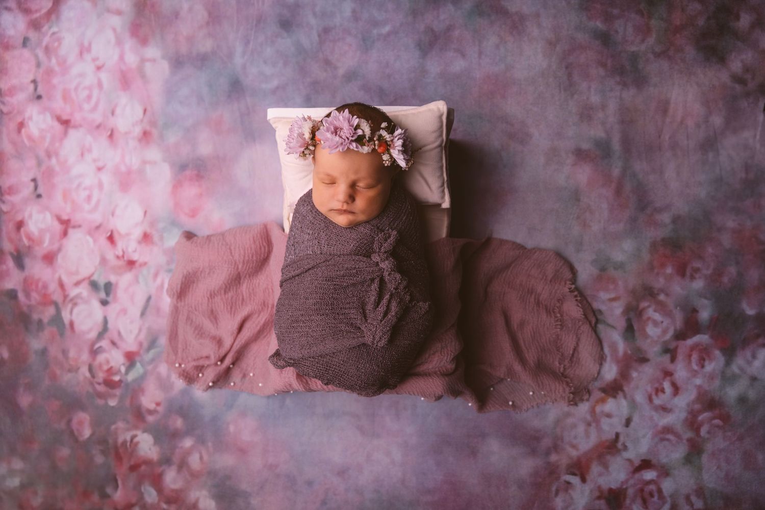 Artistic newborn portrait with pink and purple textured backdrop.