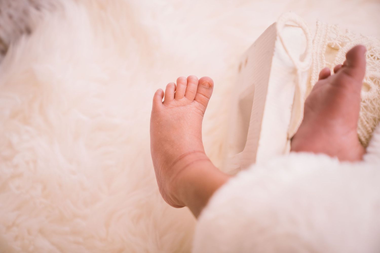 Close-up of tiny baby feet against white fabric background.