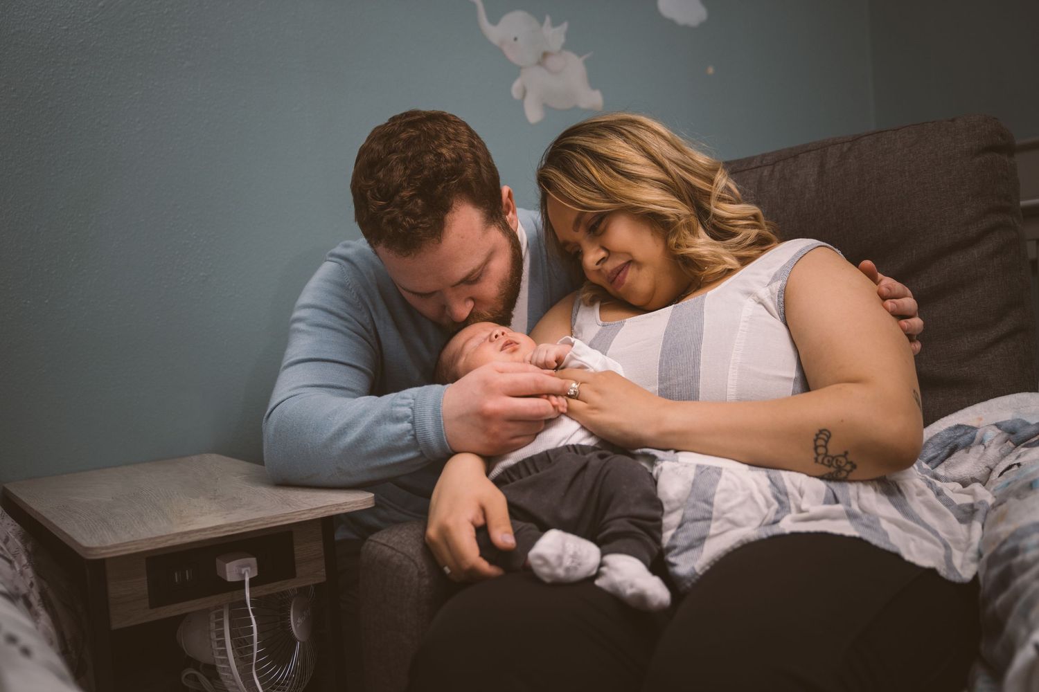Intimate family moment captured in a nursery with soft blue walls.
