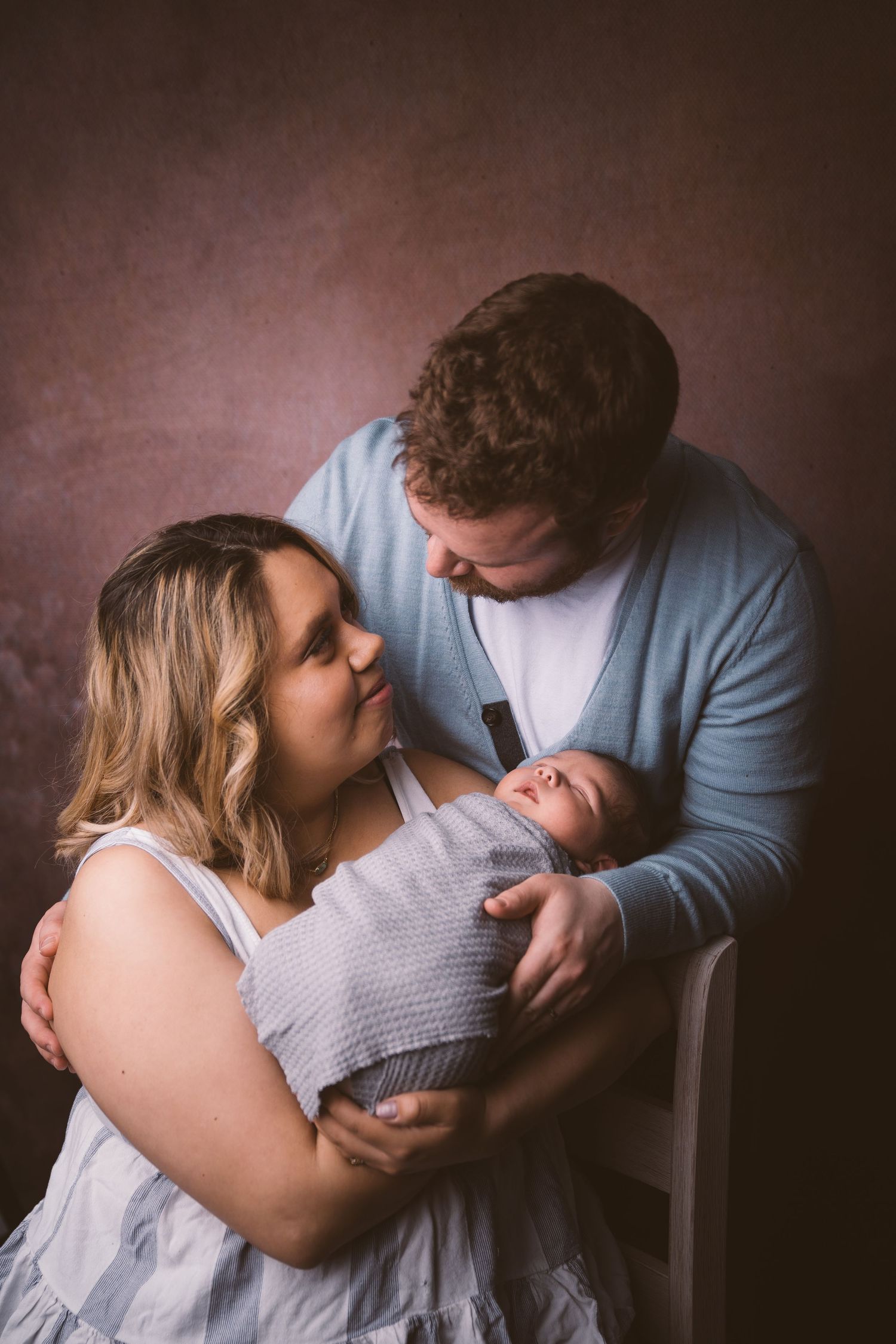 An intimate family portrait showing parents sharing a moment with their newborn.