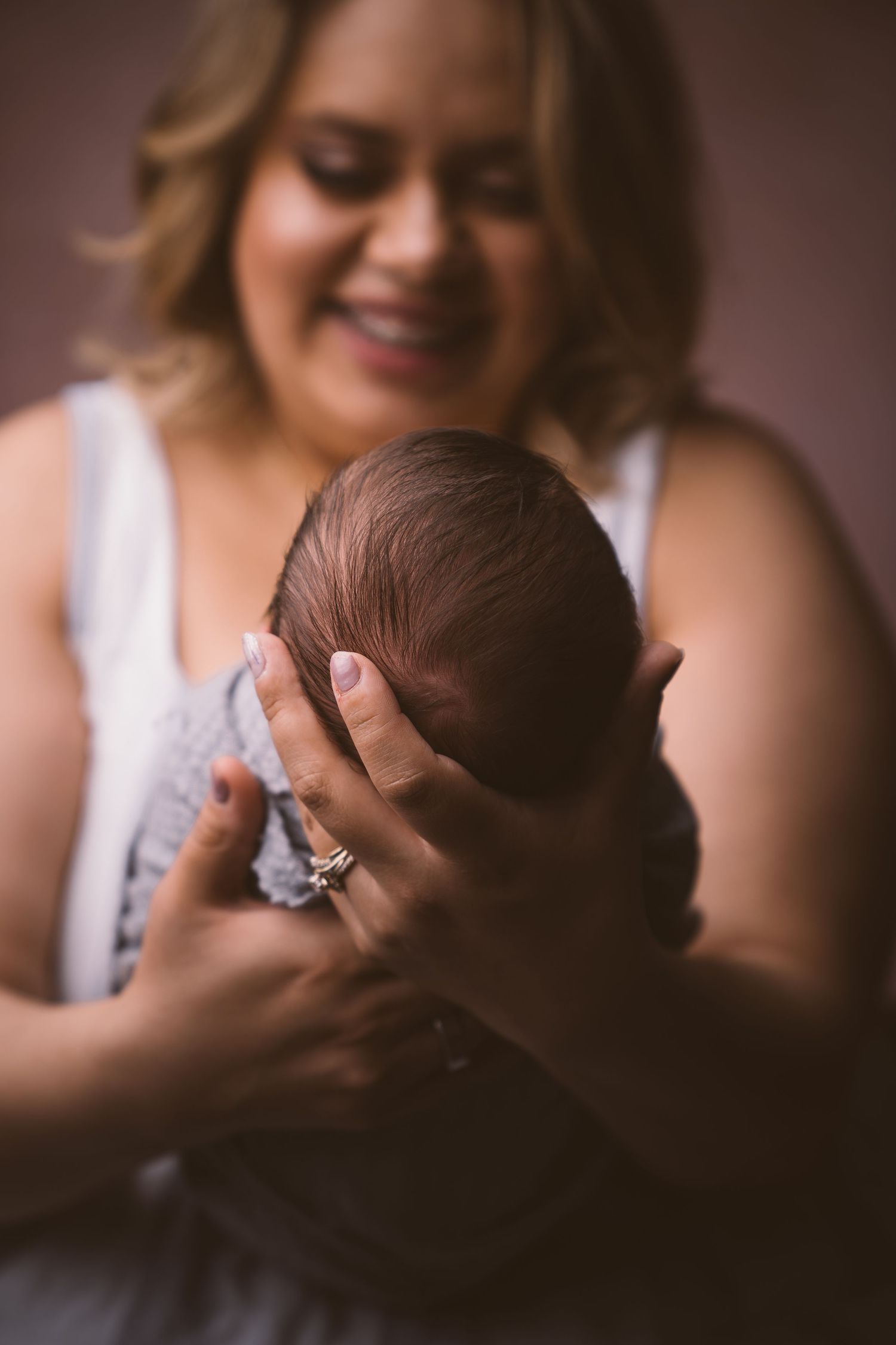 Gentle moment between parent and newborn in warm lighting.