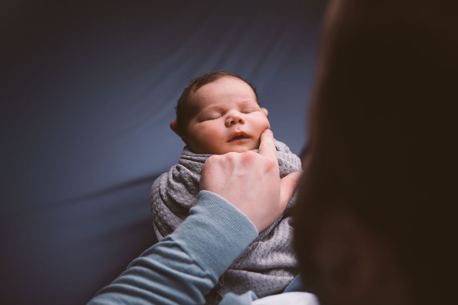 Close-up series of newborn baby being cradled in gentle hands.