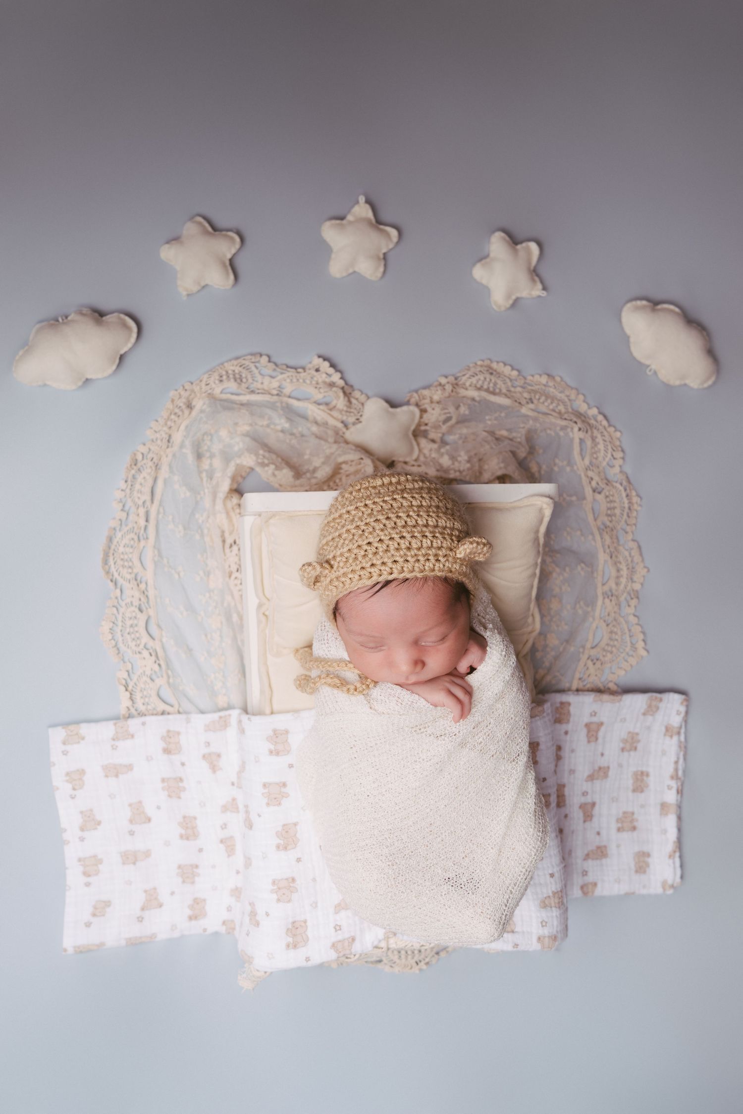 Newborn baby sleeping on white lace backdrop with decorative stars.