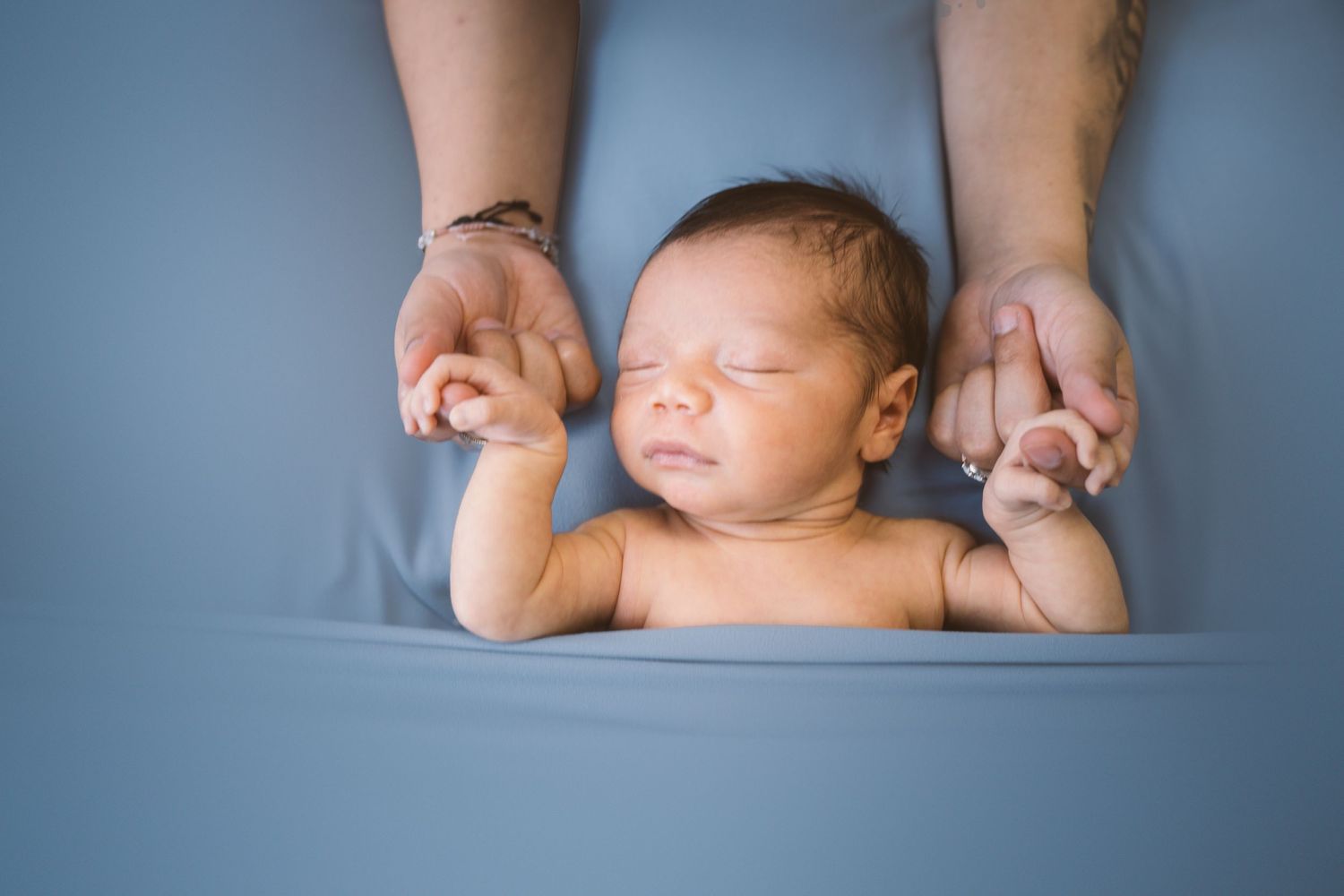Close-up artistic shots of sleeping newborn baby against blue backdrop.