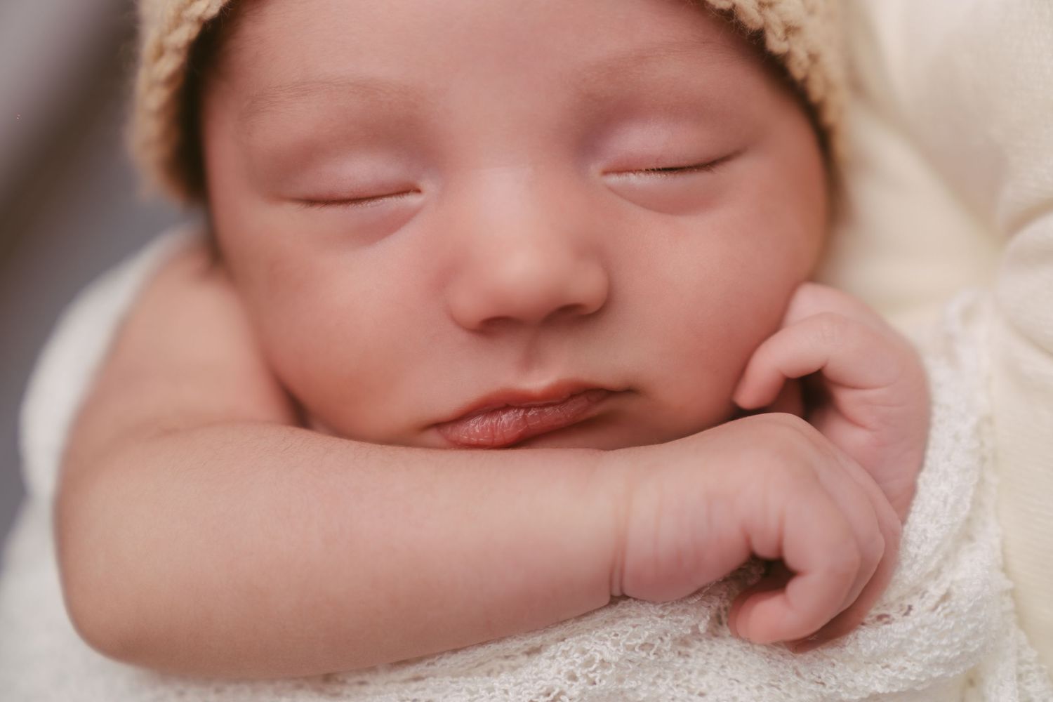Close-up portraits of peaceful sleeping newborn wrapped in white.