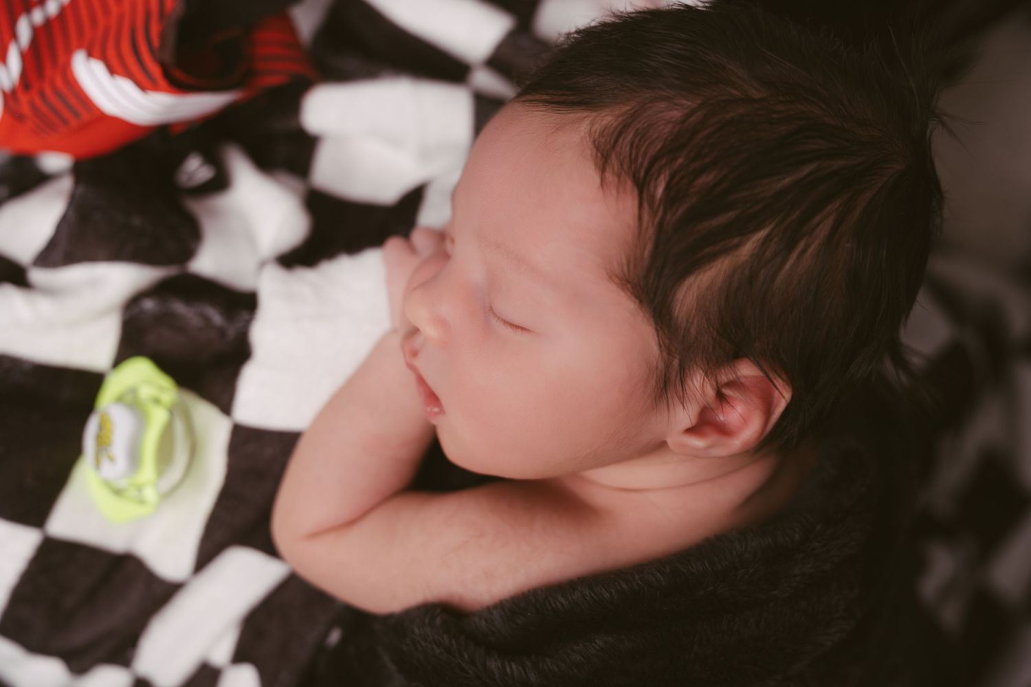 Baby sleeping on black and white checkered racing themed backdrop.