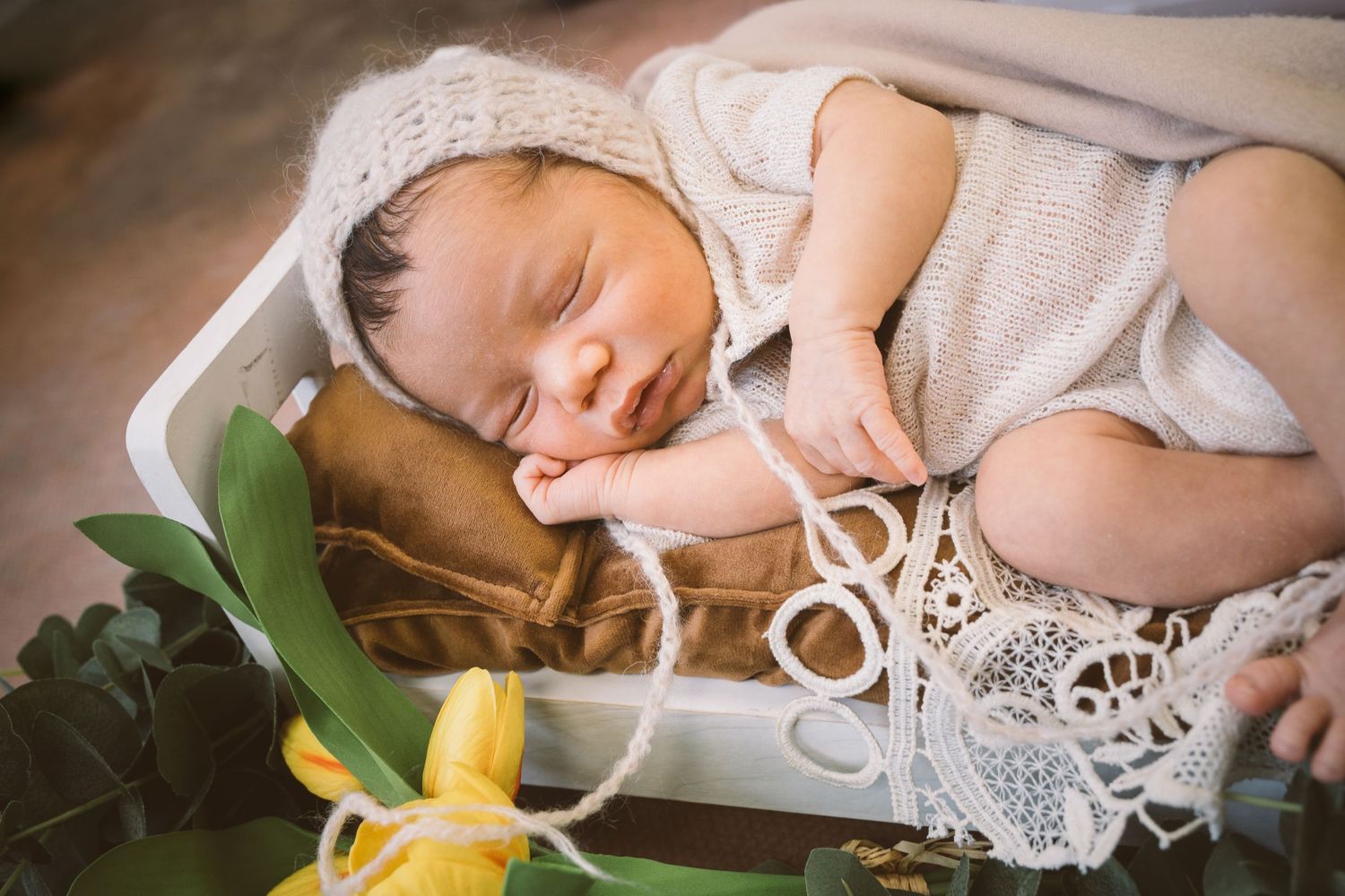 Delicate newborn photography with lace details and floral elements.