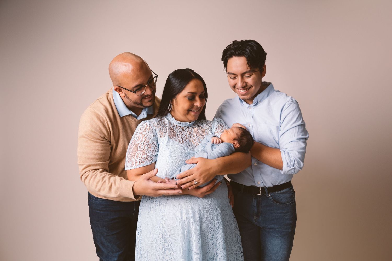 Parents holding and gazing lovingly at their newborn baby in a tender family portrait session.