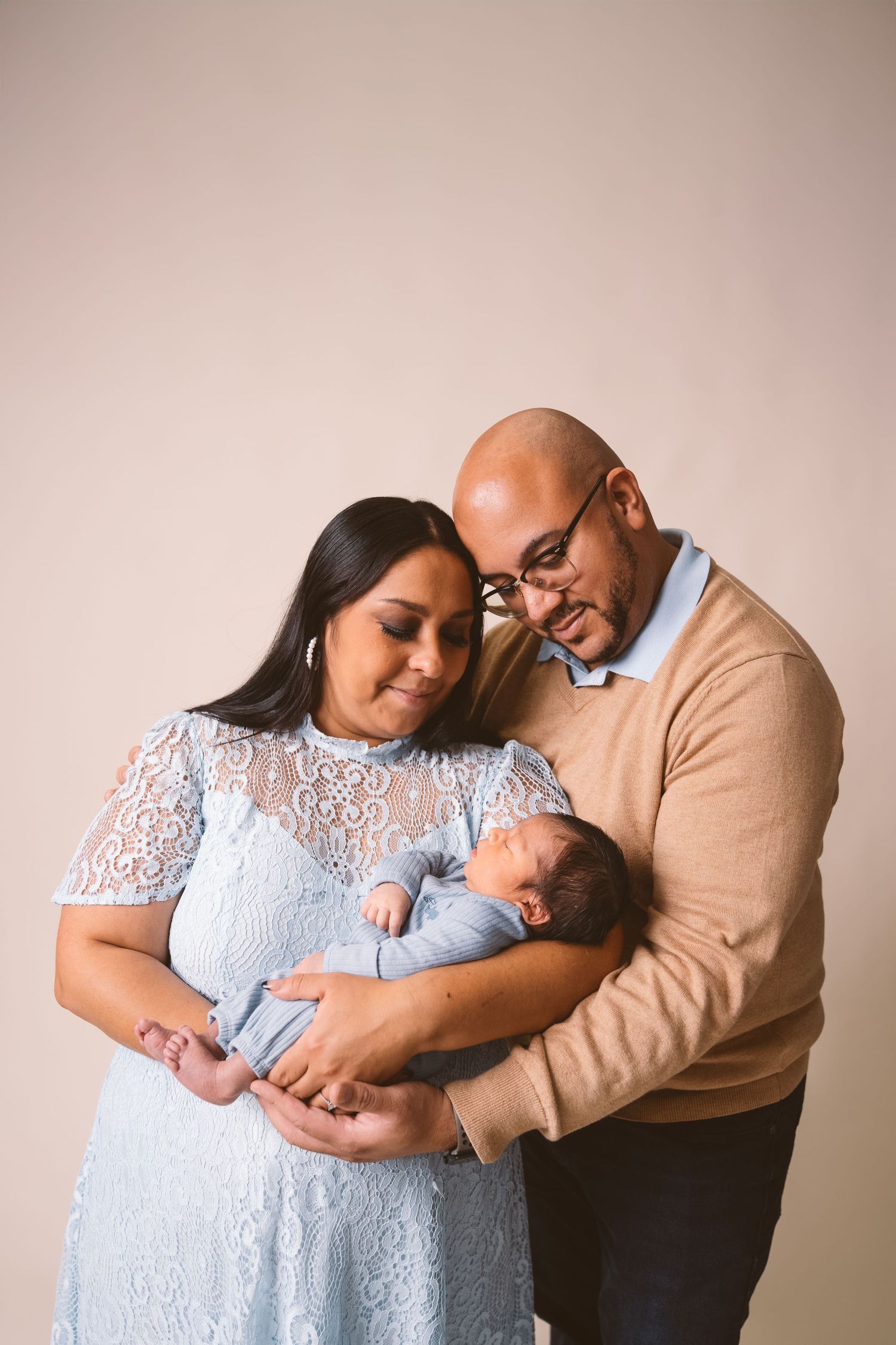Intimate family moment with newborn baby in a soft-lit studio setting.