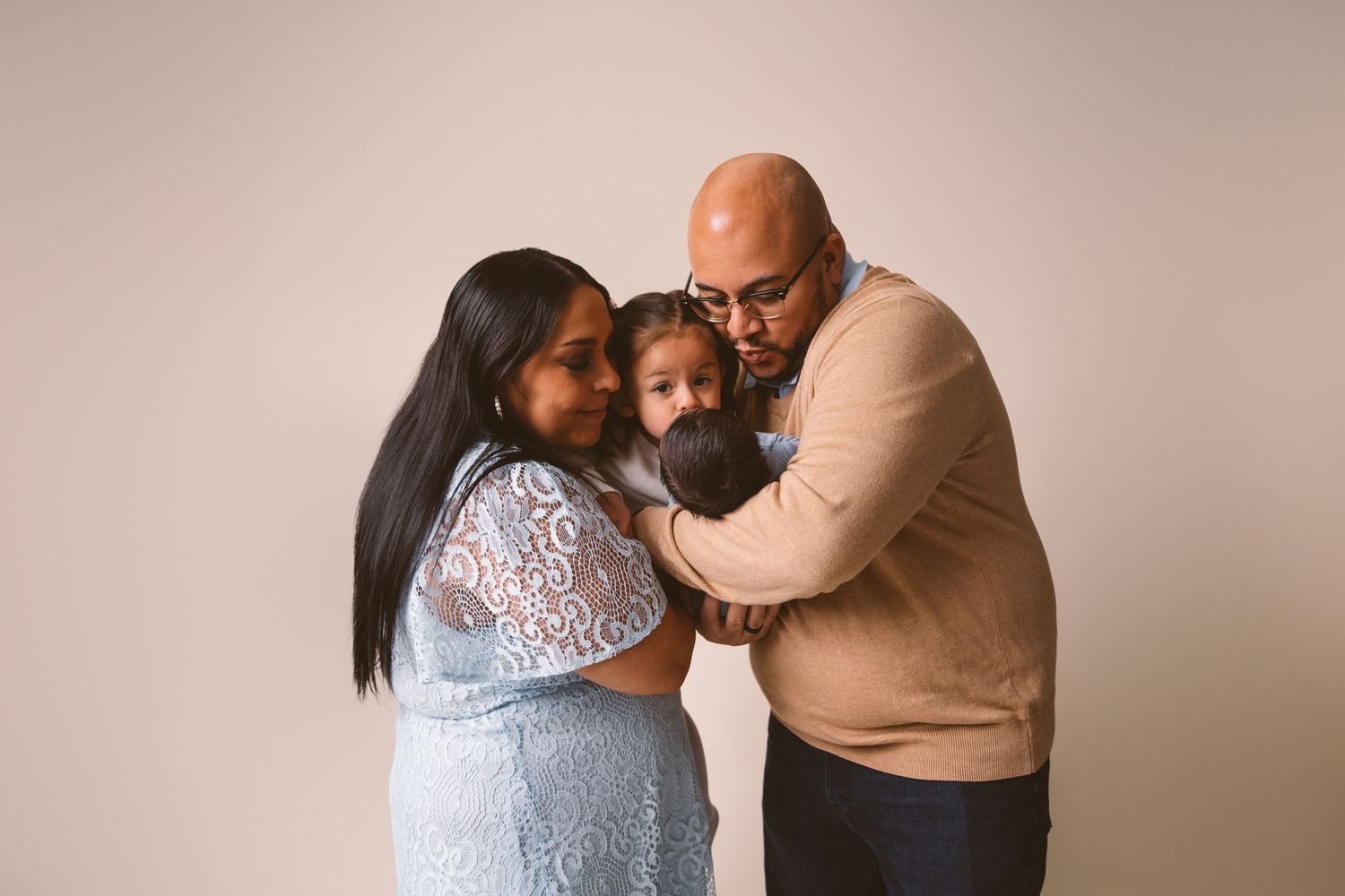 Loving family embrace captured in studio against neutral background.
