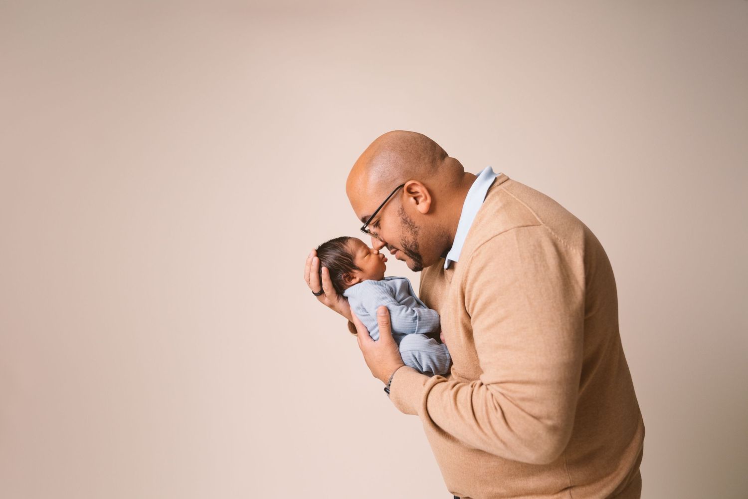 Tender moment between parent and newborn baby in studio lighting.