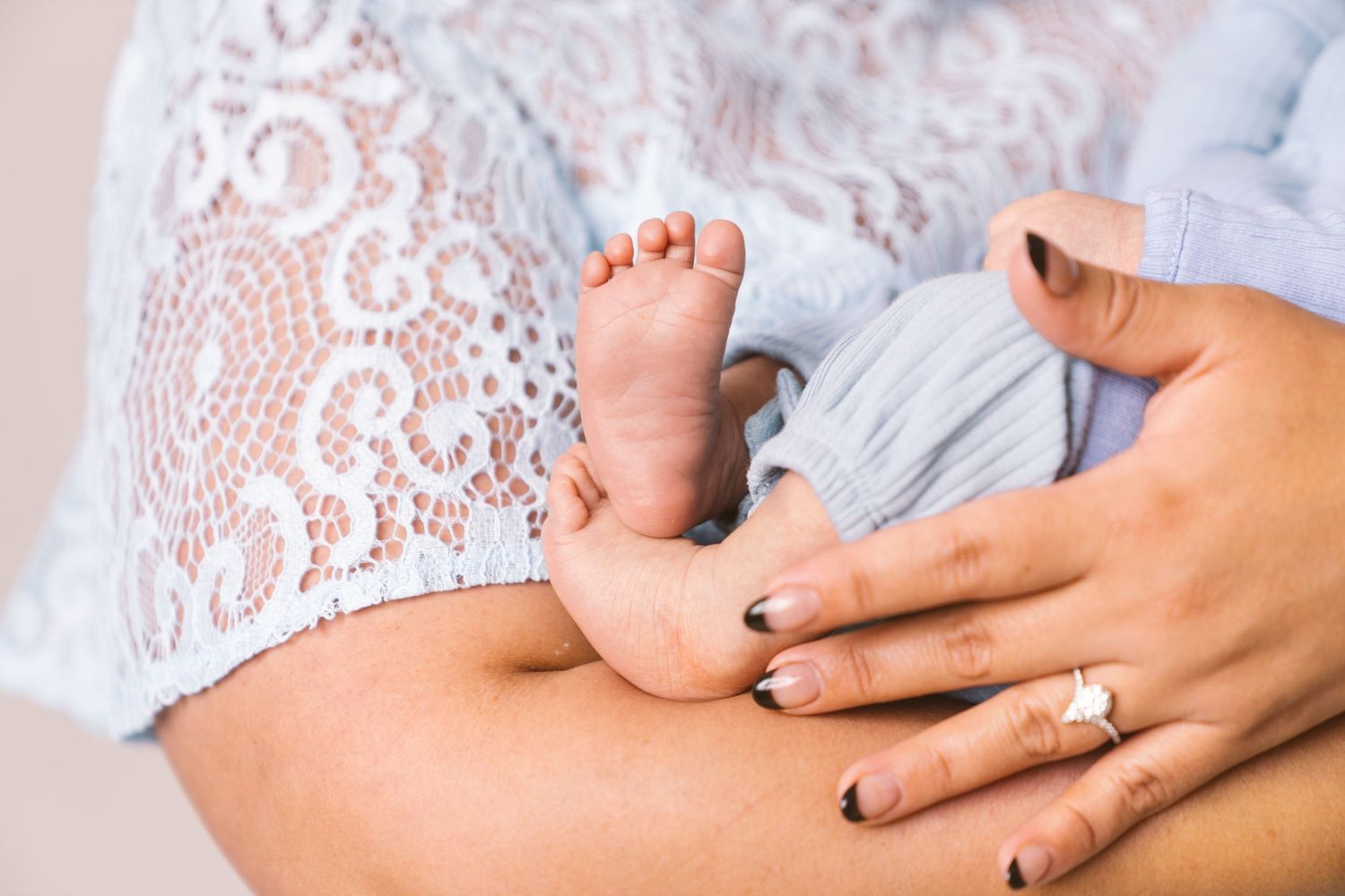 Close-up of a sleeping newborn baby in soft white lace and blue clothing.