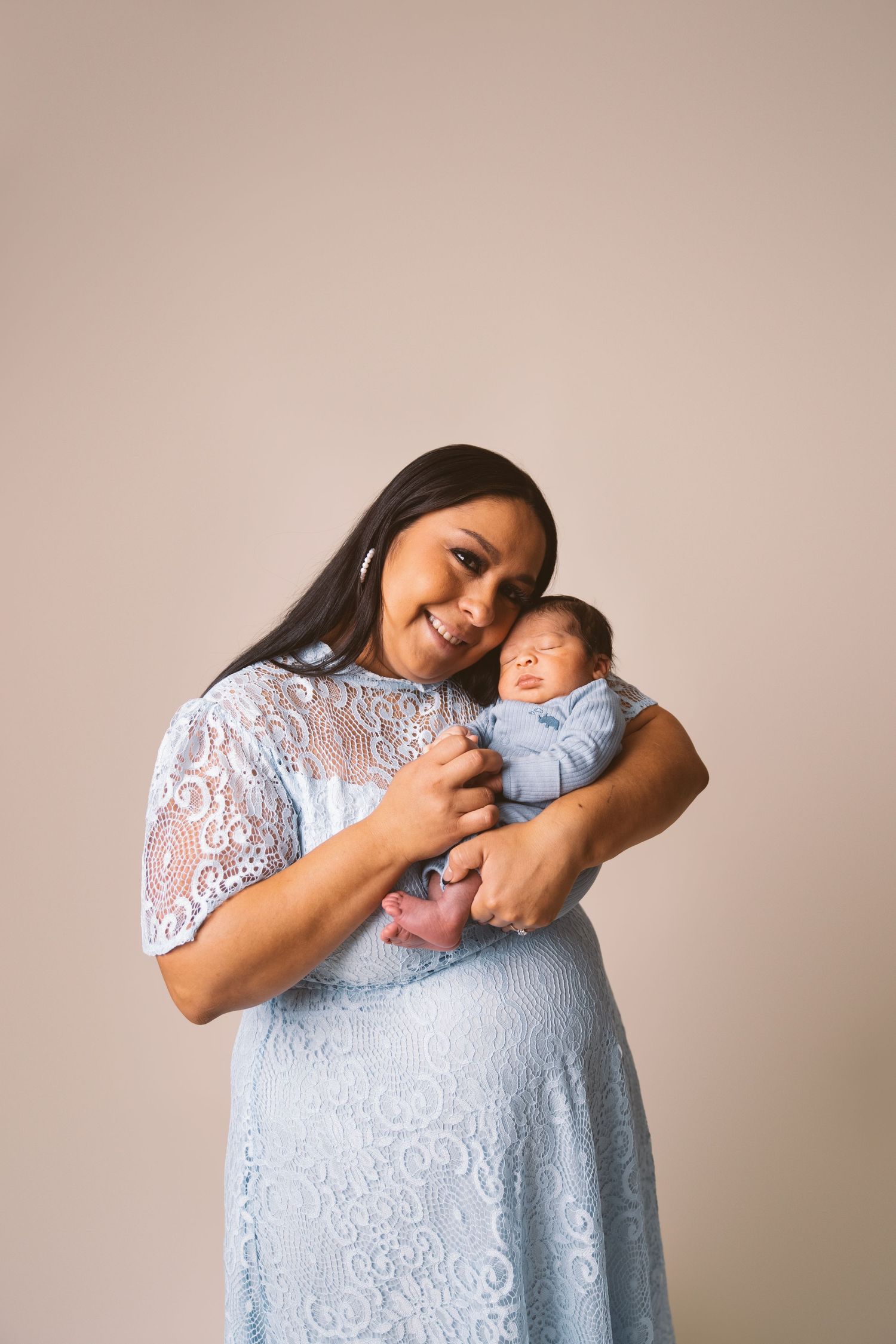 Joyful moment showing affection with a newborn baby against neutral background.