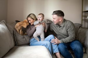 Happy family moment on a couch with their golden retriever pet.