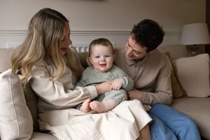 Cozy family moment on a light-colored sofa sharing smiles and laughter.