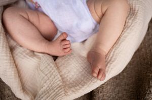 Close up of baby's bare feet and legs wrapped in white fabric.