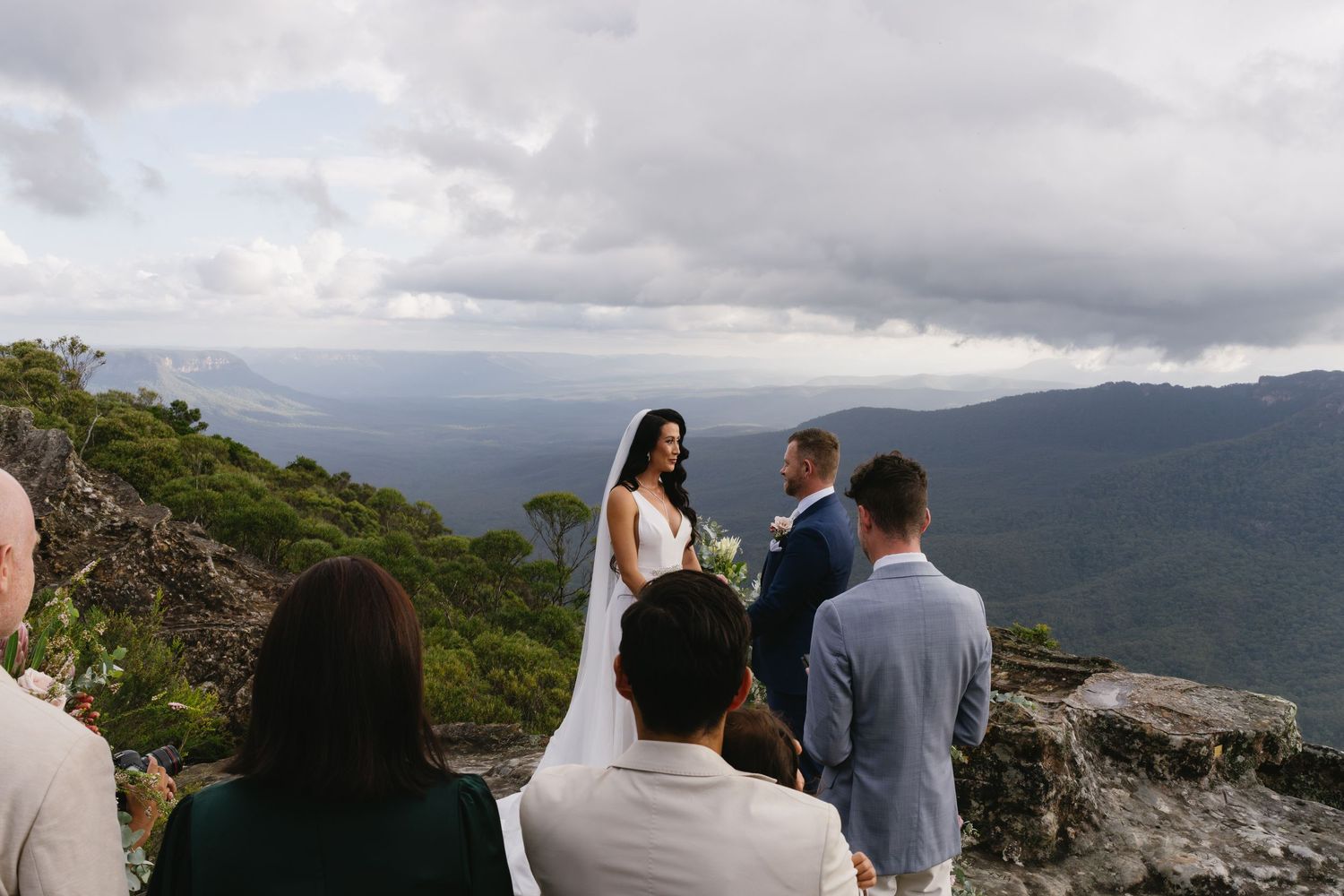 Small mountain-top wedding ceremony with guests watching the couple exchange vows.