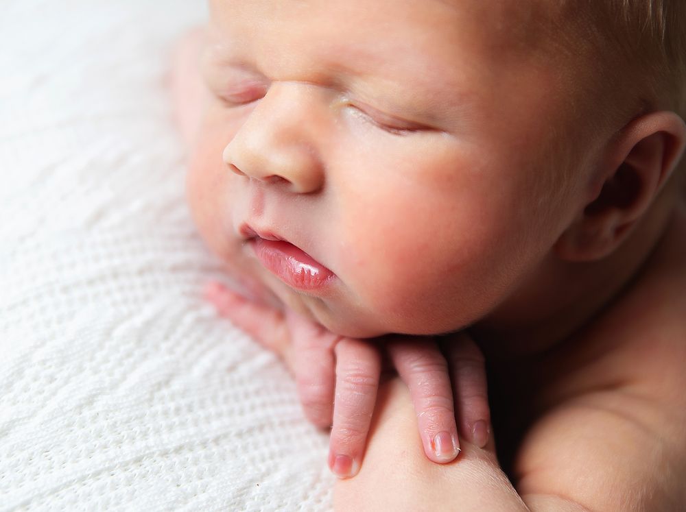 Sleeping newborn baby on white background with soft focus and delicate skin tones.