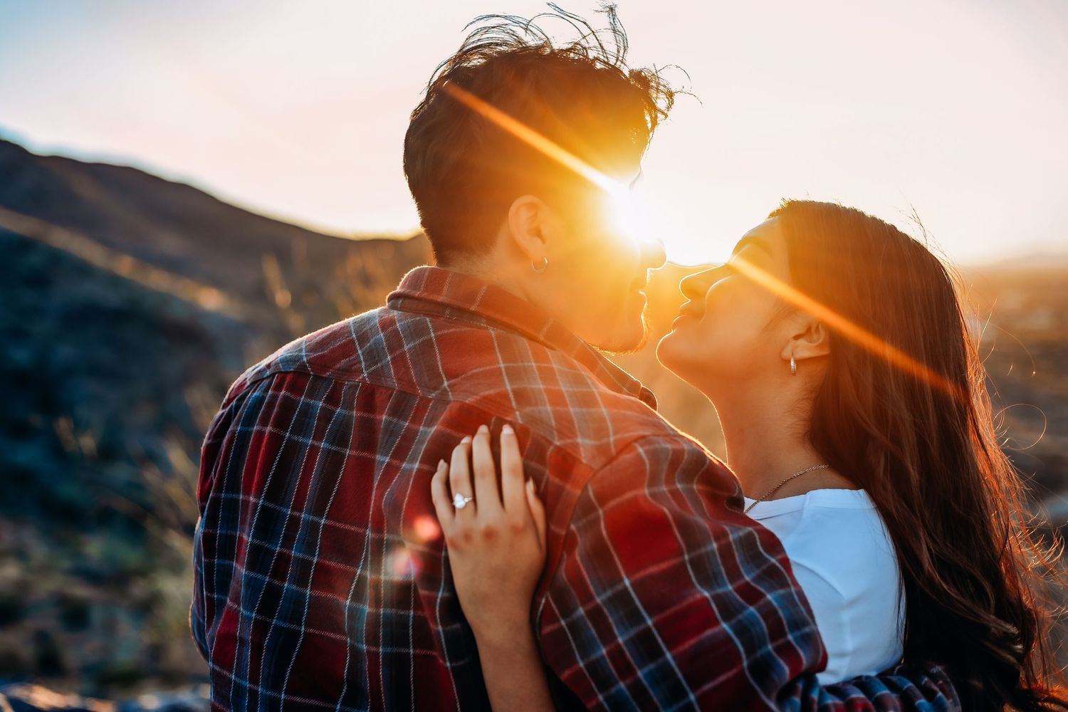Romantic couple embracing against sunset mountain backdrop for their engagement session in Phoenix
