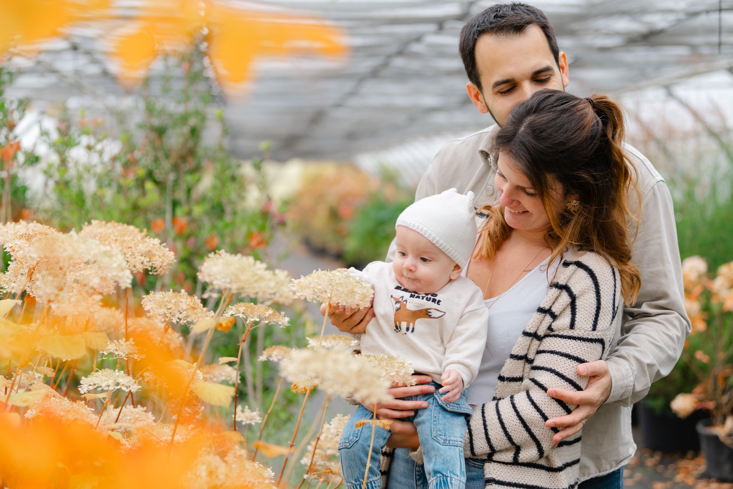 Family enjoying a tender moment among orange wildflowers in a garden.
