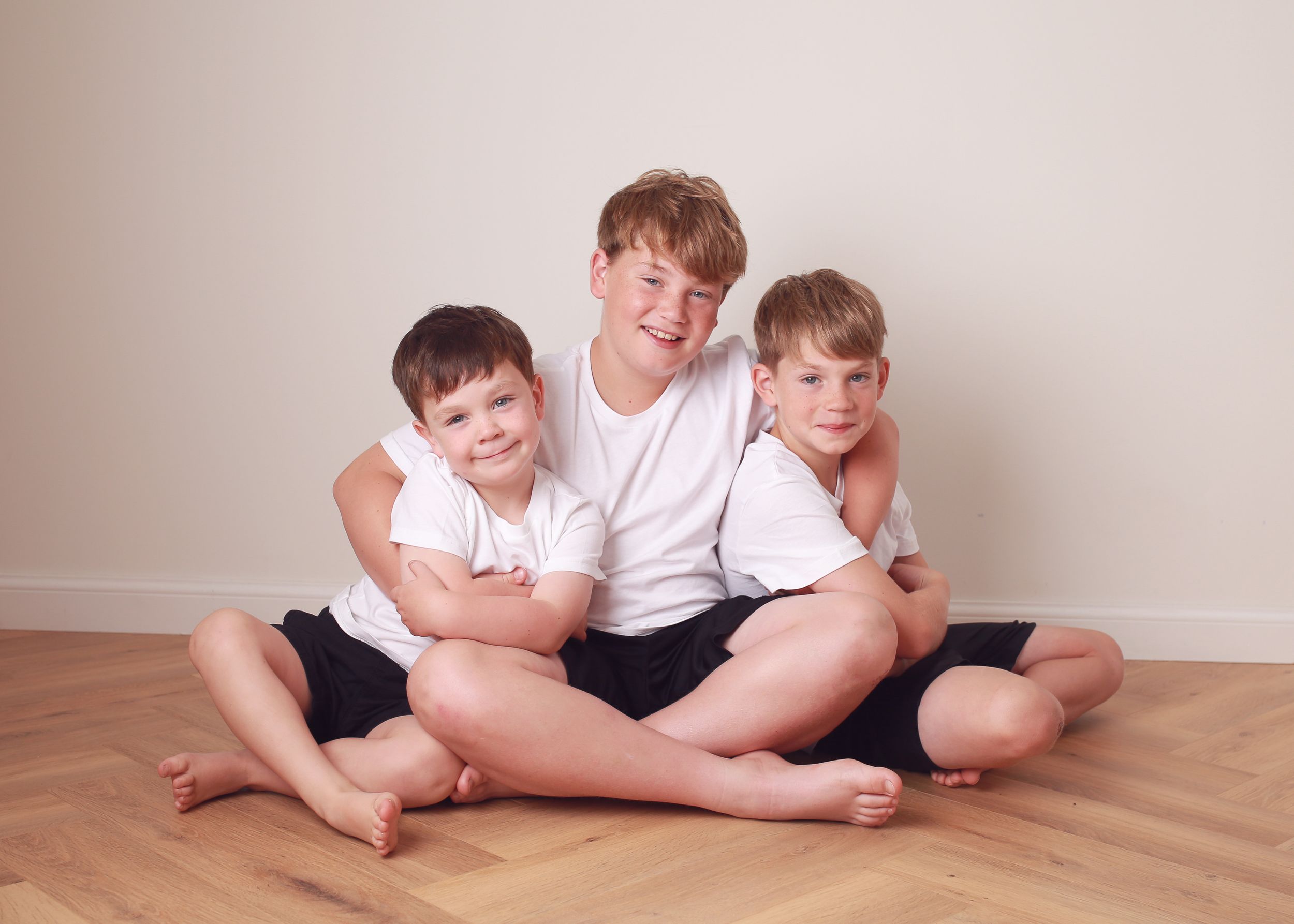 Three brothers sharing a playful and loving moment, capturing their strong sibling bond and joyful energy during a family photography sessio