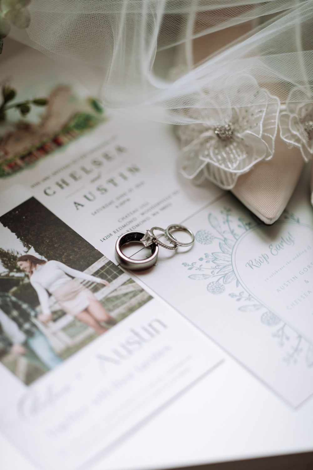 Wedding invitation suite with elegant floral details and silver wedding rings on white paper.