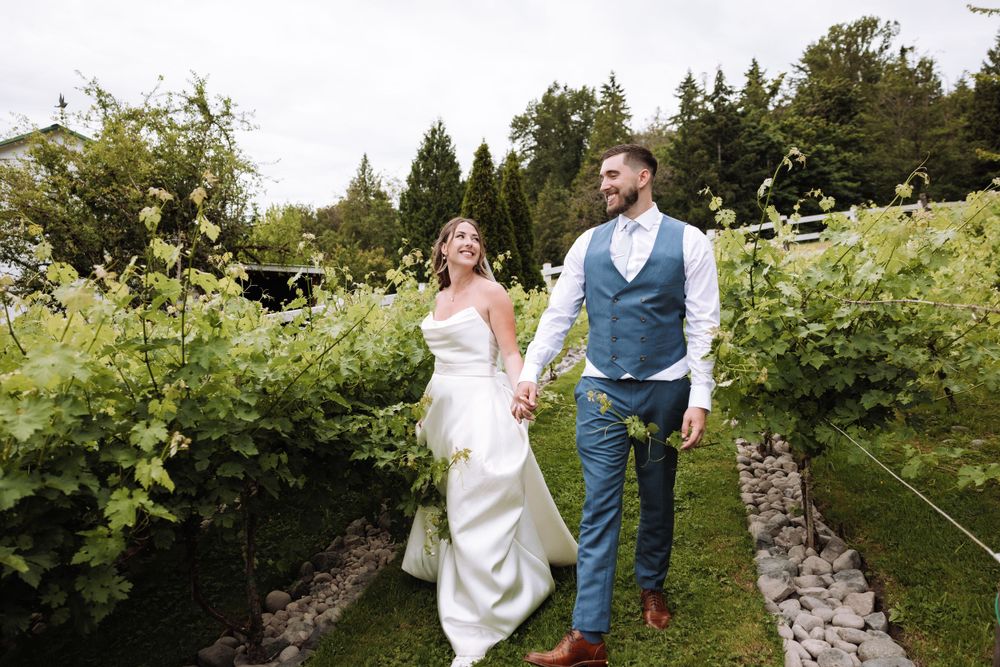 Couple walking through a lush vineyard garden path on their wedding day.