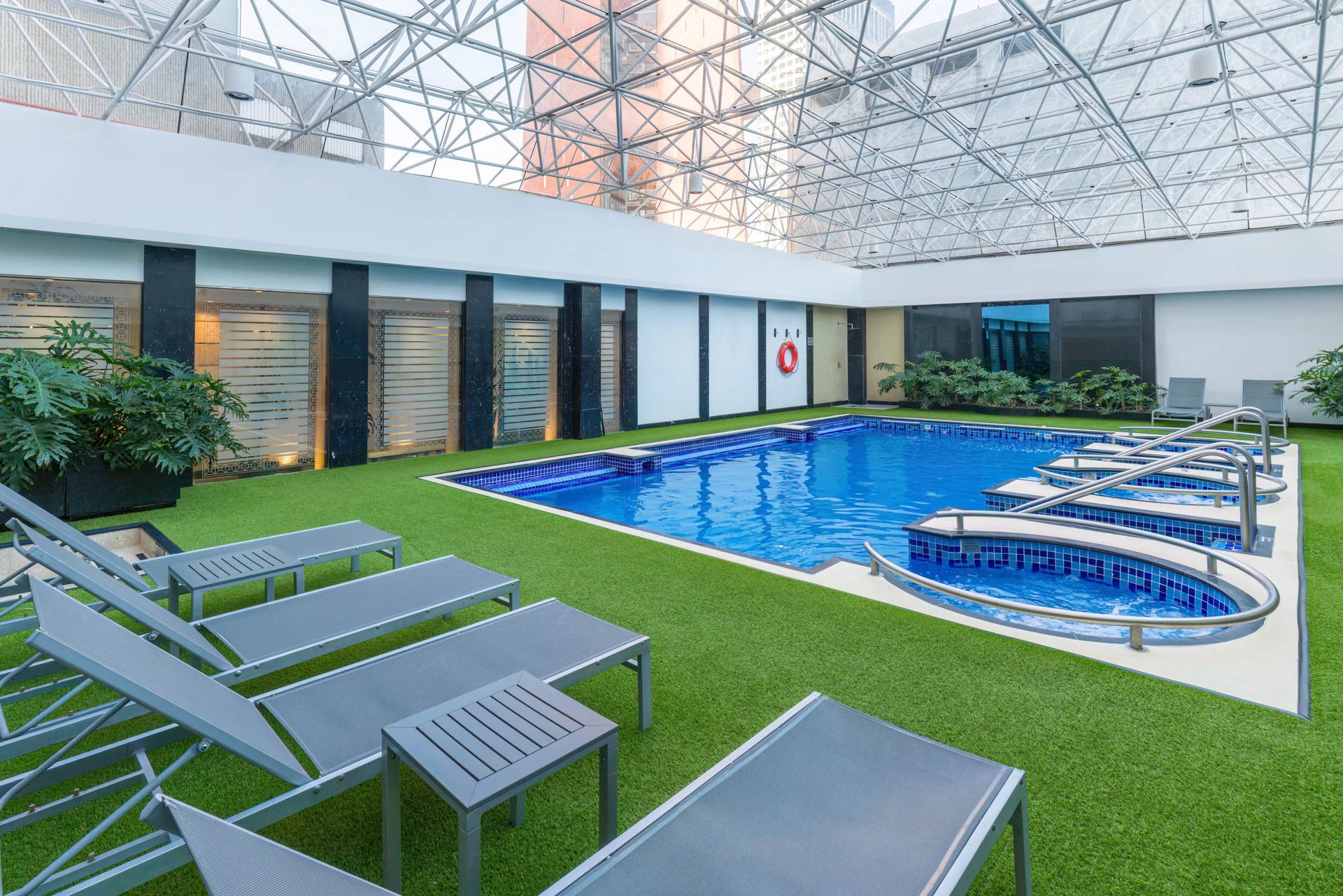 Luxury indoor swimming pool with loungers and artificial turf surroundings. Barcelo Mexico City Reforma.
