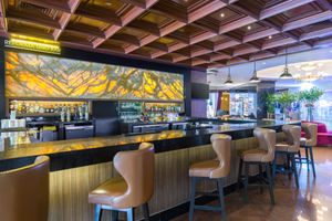 Stylish Lobby Bar area with wooden coffered ceiling and dramatic yellow mural marble backdrop. Barcelo Mexico Reforma.