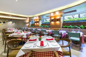 Casual dining room with checkered tablecloths, wooden chairs, and illuminated green wall accents. Fontana Barcelo Mexico Reforma.