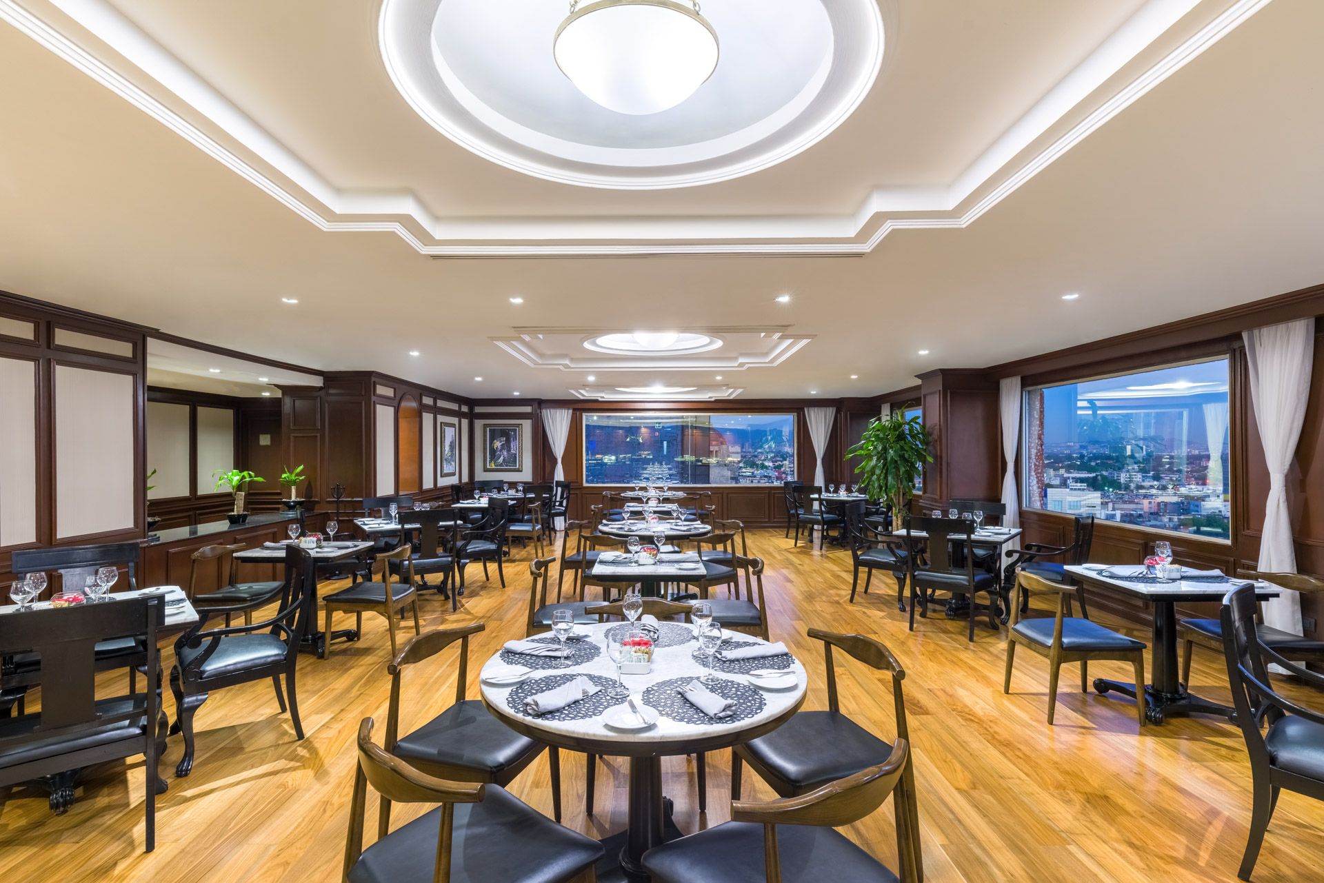 Spacious restaurant dining room with circular tables, modern chairs, and elegant ceiling design. Premium Level Barcelo Mexico Reforma.