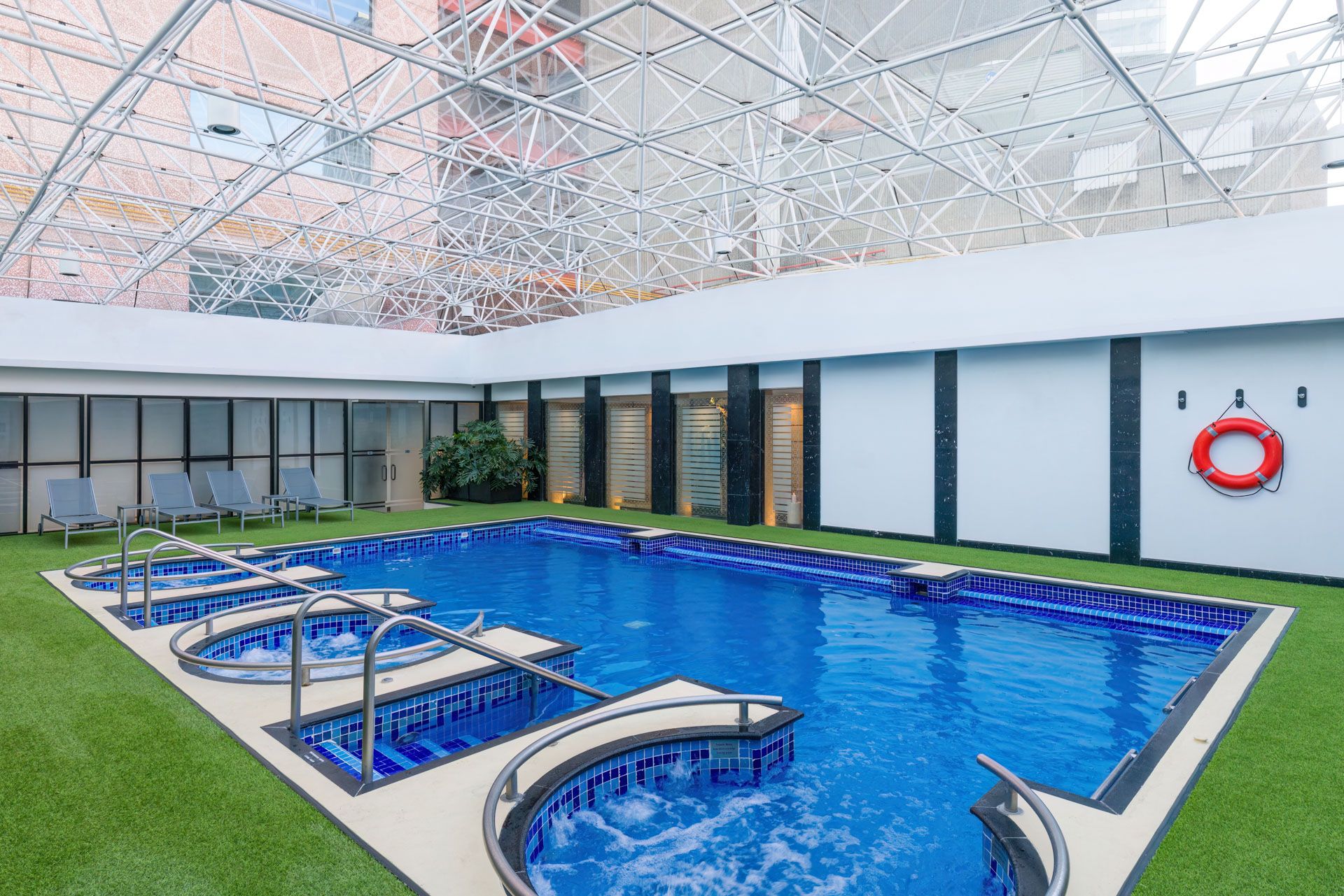 Luxury indoor swimming pool with loungers and artificial turf surroundings. Barcelo Mexico City Reforma. Multiple spa sections.
