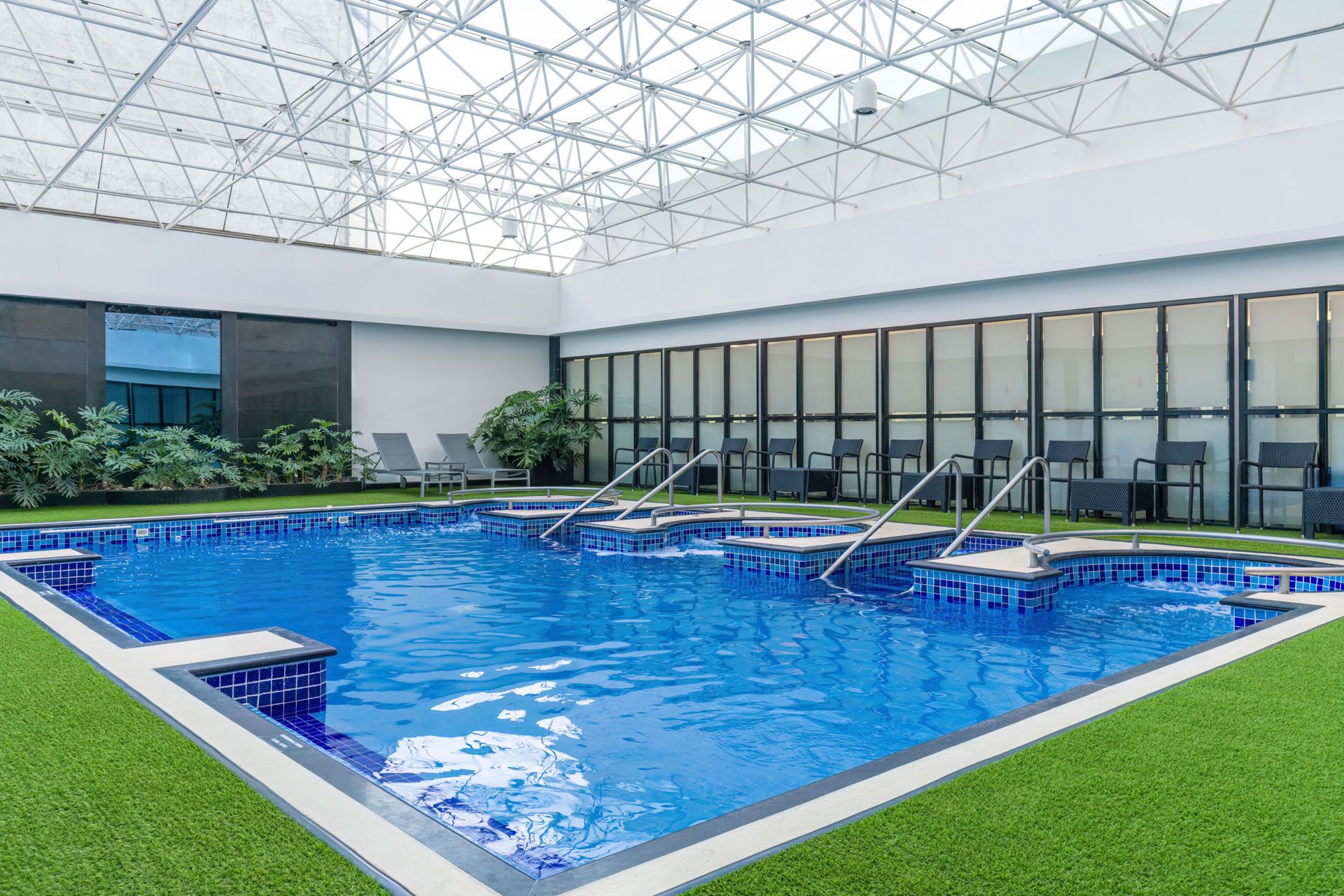 Luxury indoor swimming pool with loungers and artificial turf surroundings. Barcelo Mexico City Reforma. Multiple spa sections.