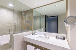 Luxurious hotel bathroom featuring marble countertop, large mirror and geometric tile accent wall. Barcelo Mexico Reforma