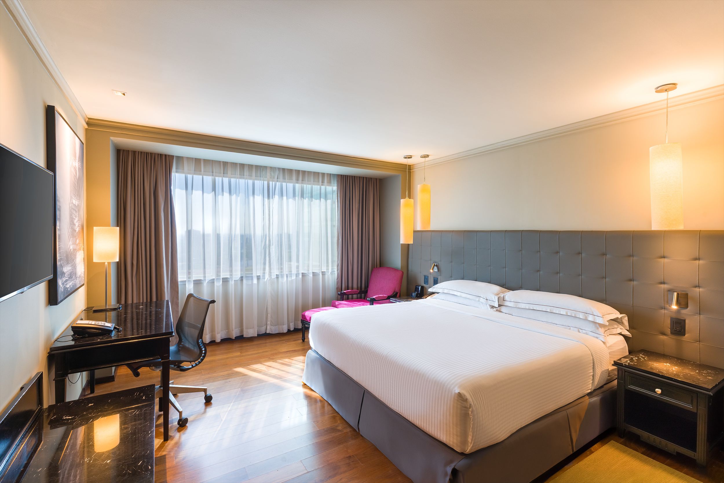 Contemporary hotel room with large windows, neutral decor and modern furnishings. Barcelo Mexico Reforma.