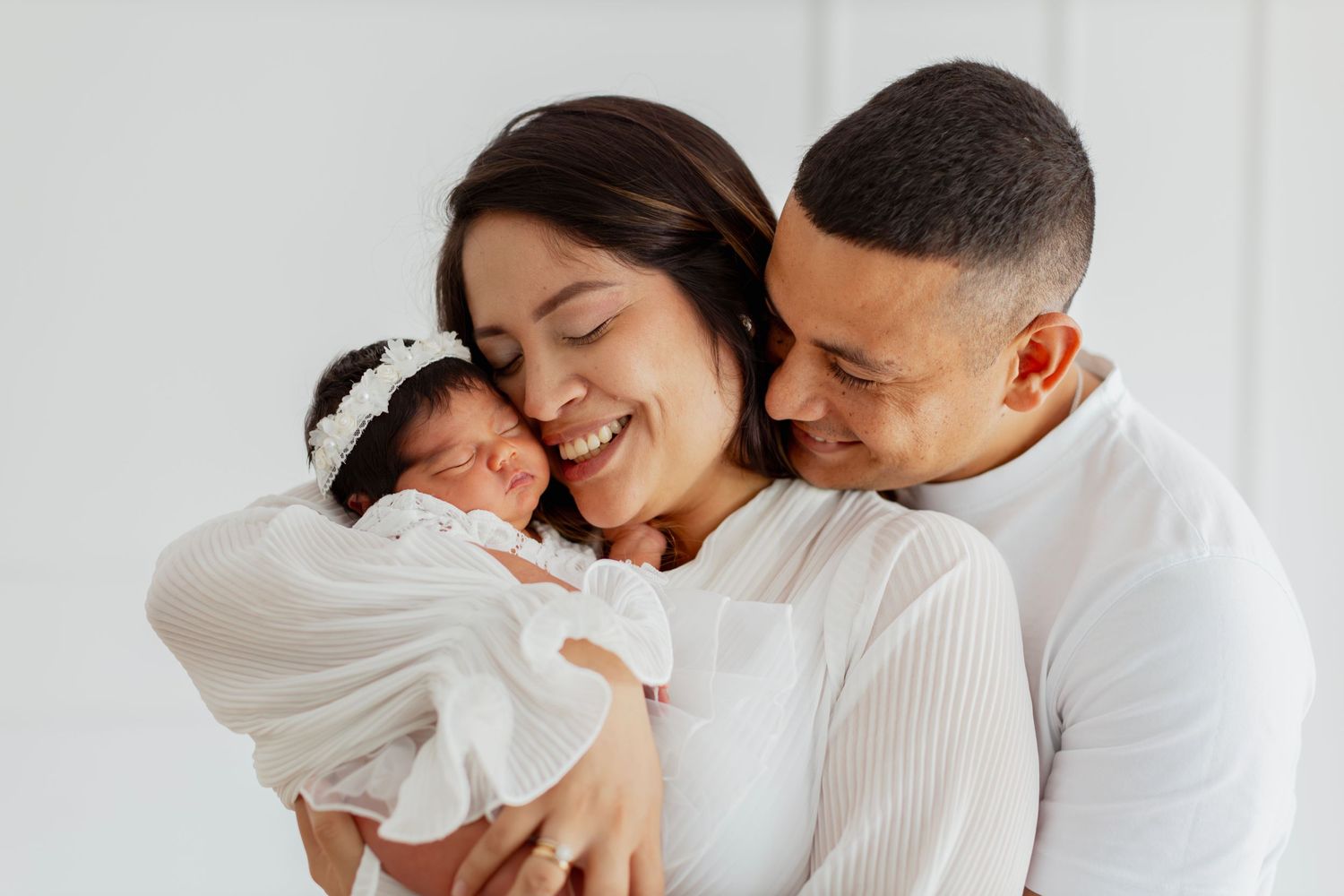 An intimate family portrait in white against a clean minimal background.